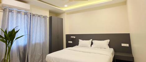 A modern bedroom with a bed, bedside tables, a ceiling fan, and an air conditioning unit.