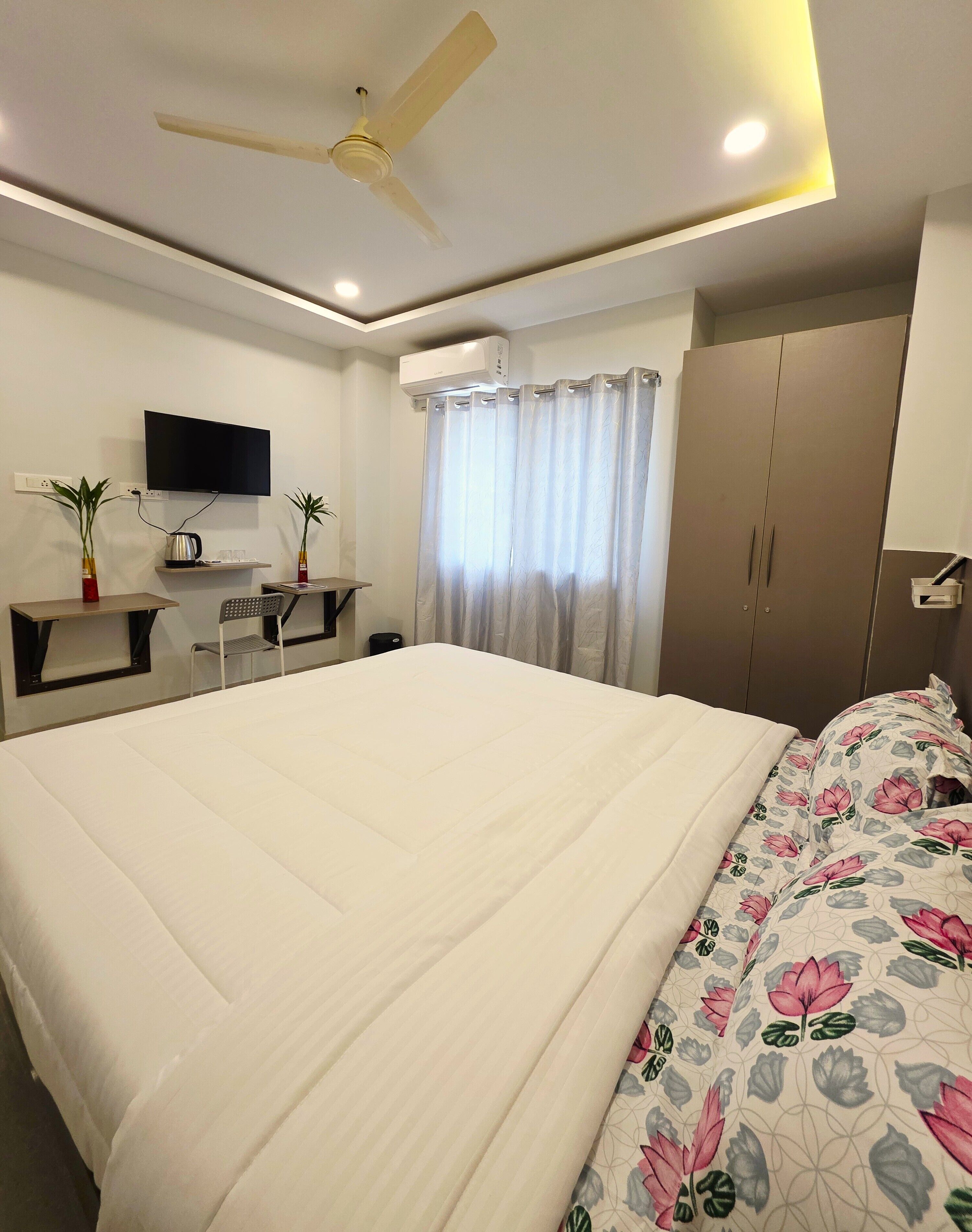 Una camera da letto con un letto grande, una scrivania con una sedia, una televisione e un armadio.