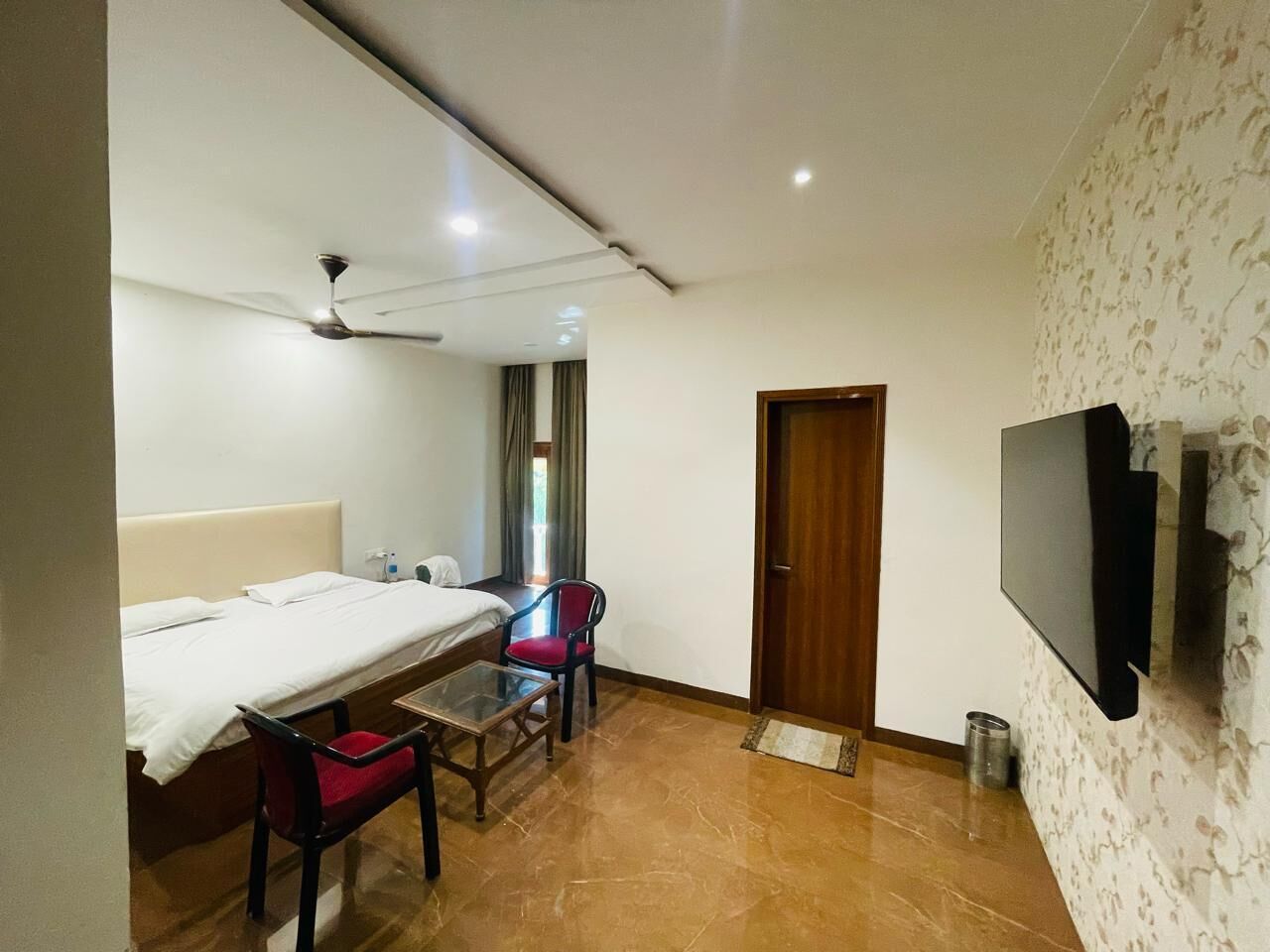 Une chambre d’hôtel avec un lit, un bureau avec une chaise, une télévision et une porte.
