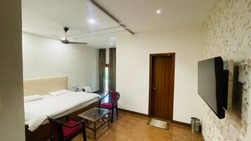 Une chambre d’hôtel avec un lit, un bureau avec une chaise, une télévision et une porte.
