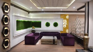 Una sala moderna con un sofá seccional, una mesa de centro y un diseño tipo césped verde montado en la pared.