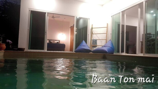 A swimming pool with blue bean bags and a sliding glass door leading to a room.