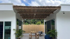 A covered outdoor patio with a pool, seating, and potted plants.
