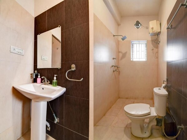 A bathroom with a sink, mirror, toilet, shower, and a window.