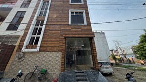 A multi-story building with a modern design, featuring a combination of stone and wood paneling on the facade. - Hotel Vrinda orchid Inn (Vrindavan)
