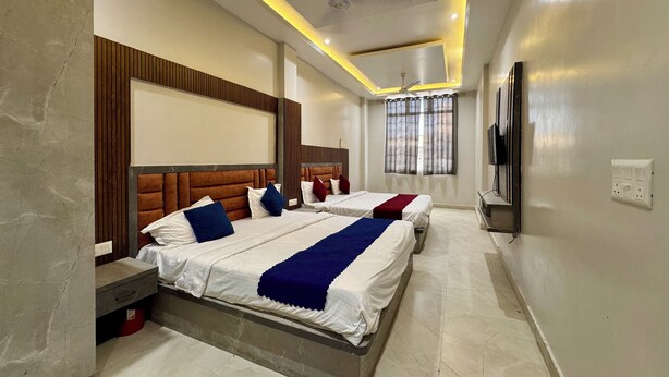 A hotel room with two beds, a TV, and a ceiling fan. - Hotel Vrinda orchid Inn (Vrindavan)