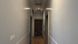 A narrow hallway with white walls and a wooden floor. - Hotel Vrinda orchid Inn (Vrindavan)