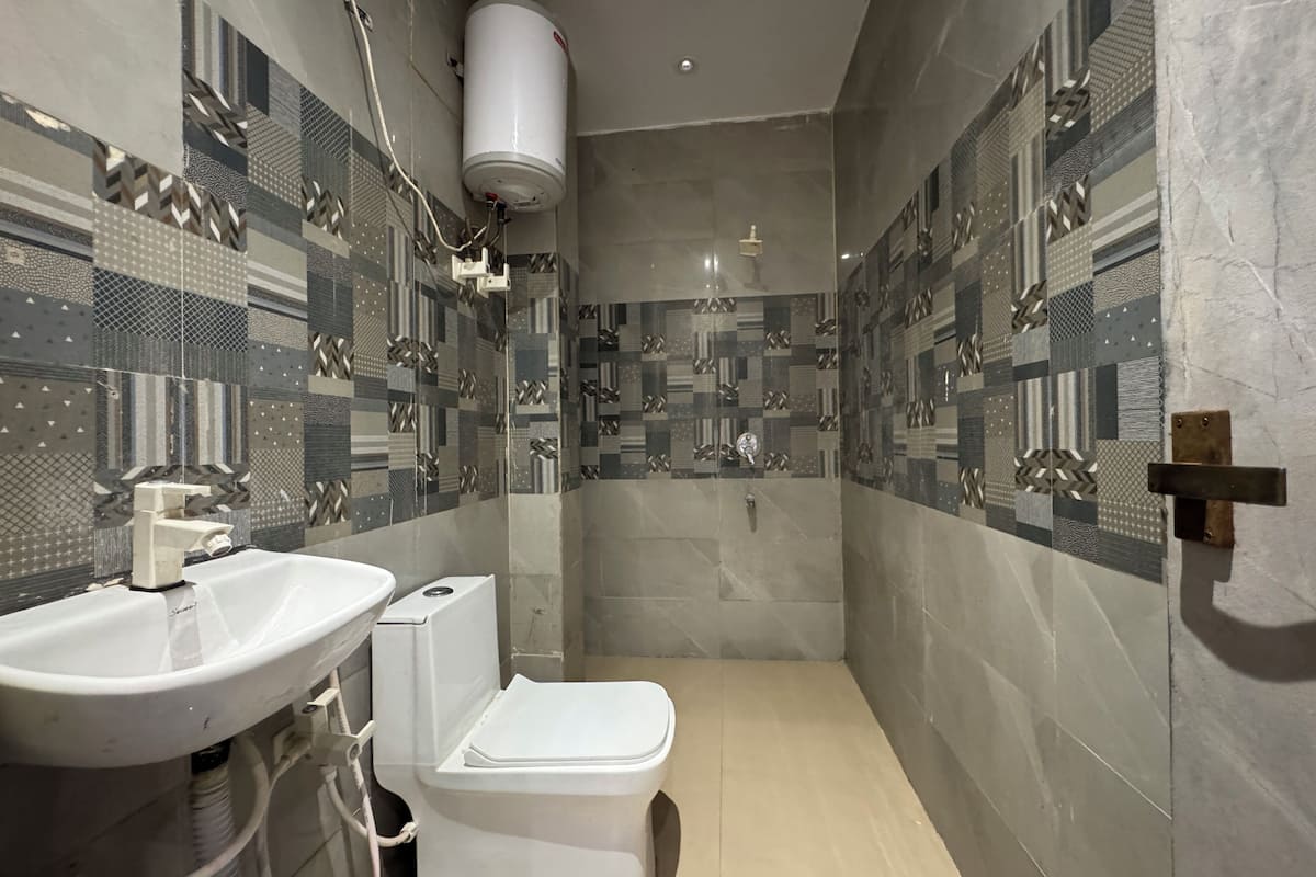 A modern bathroom with a sink, toilet, and shower. The walls are tiled with geometric patterns.