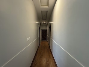 A narrow hallway with wooden flooring and white walls. - Hotel Vrinda orchid Inn (Vrindavan)