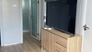 Ein Zimmer mit Holzschrank, Flachbildfernseher und einer Schiebetür zum Badezimmer.