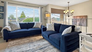 Ein Wohnzimmer mit zwei dunkelblauen Sofas, einem gemusterten Teppich und einer Chandelier.