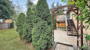 Eine Holz-Pergola mit einer Treppe, die zu einer Terrassenfläche führt.