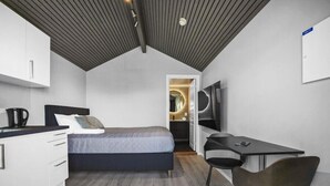 A compact bedroom with a bed, a desk, and a chair. - Nordica Resort Florø (Kinn)