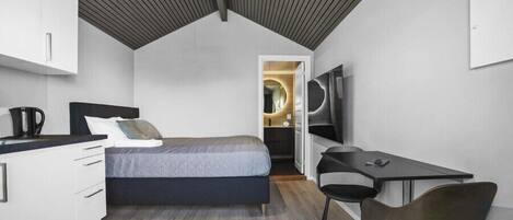 A compact bedroom with a bed, a desk, and a chair.