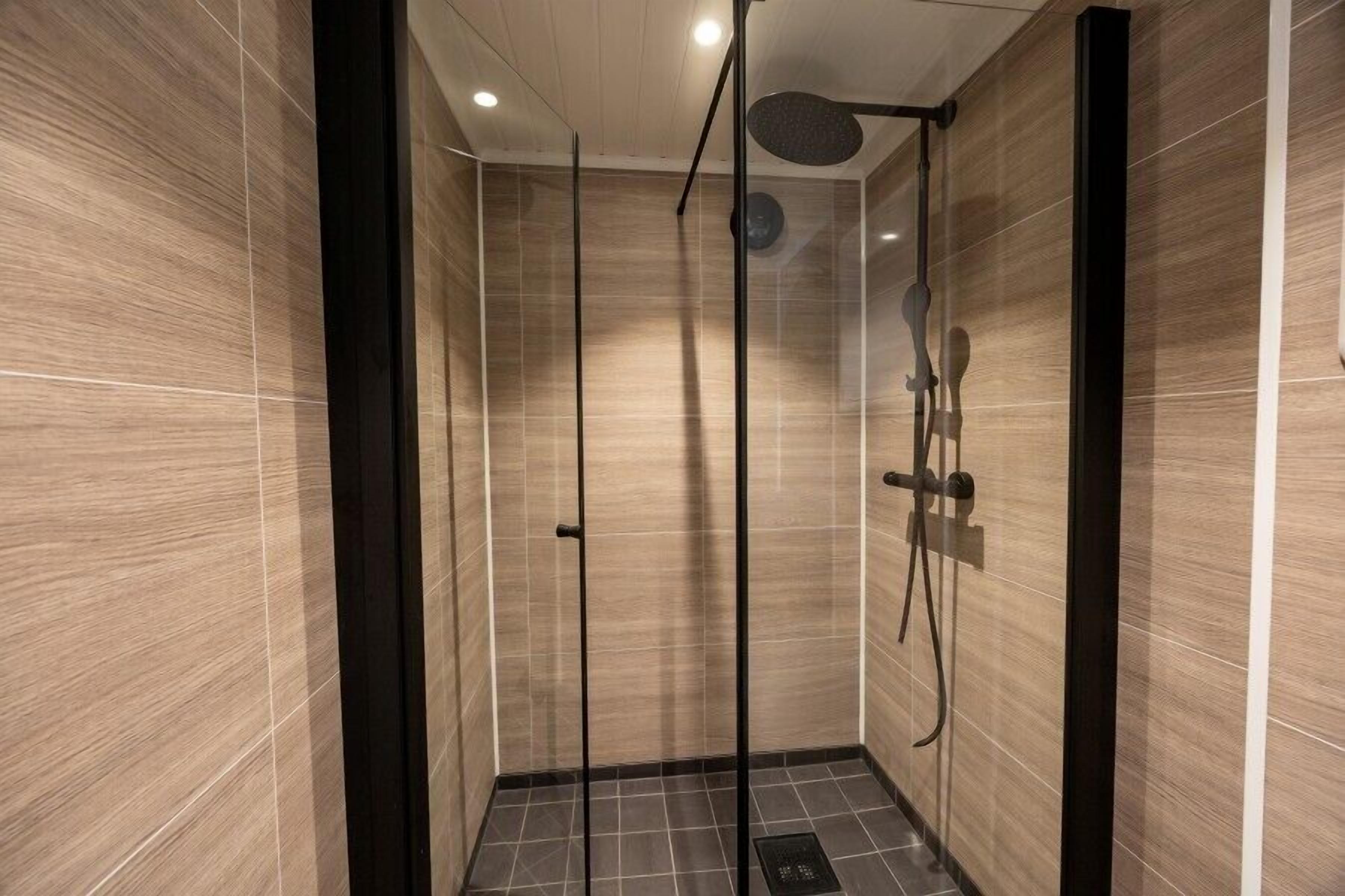 Eine moderne Dusche mit Glastür, Duschbrause und einer fest installierten Bedienfeld.