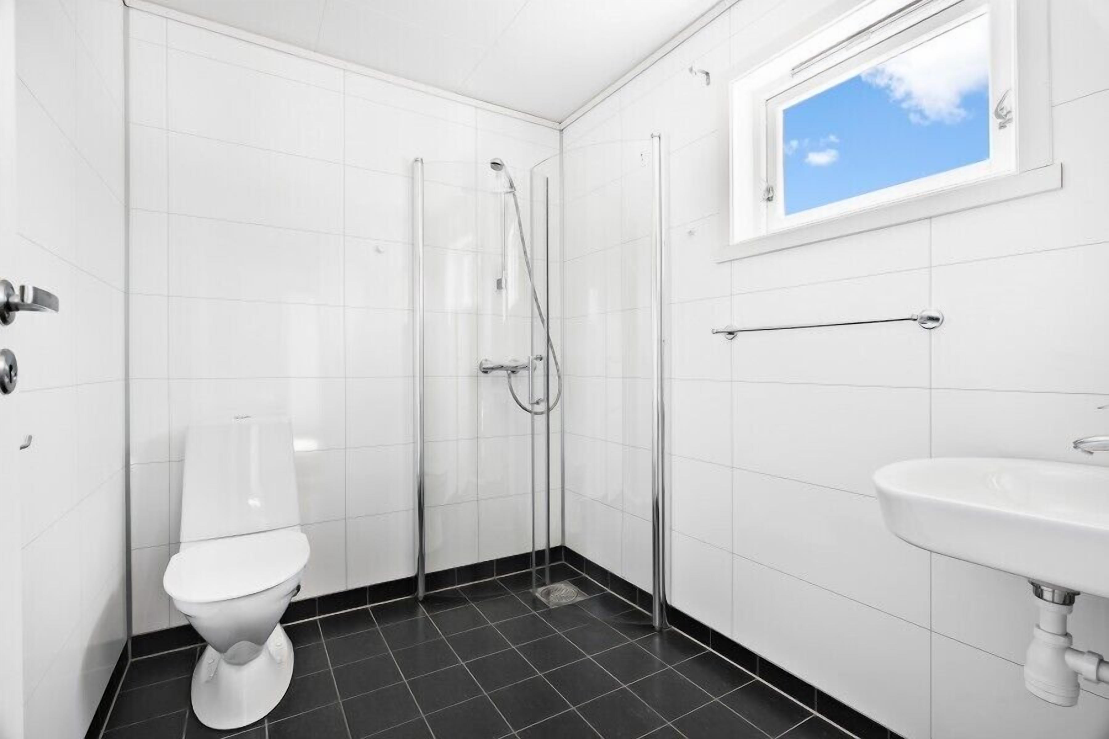 A bathroom with a toilet, a shower, and a sink.