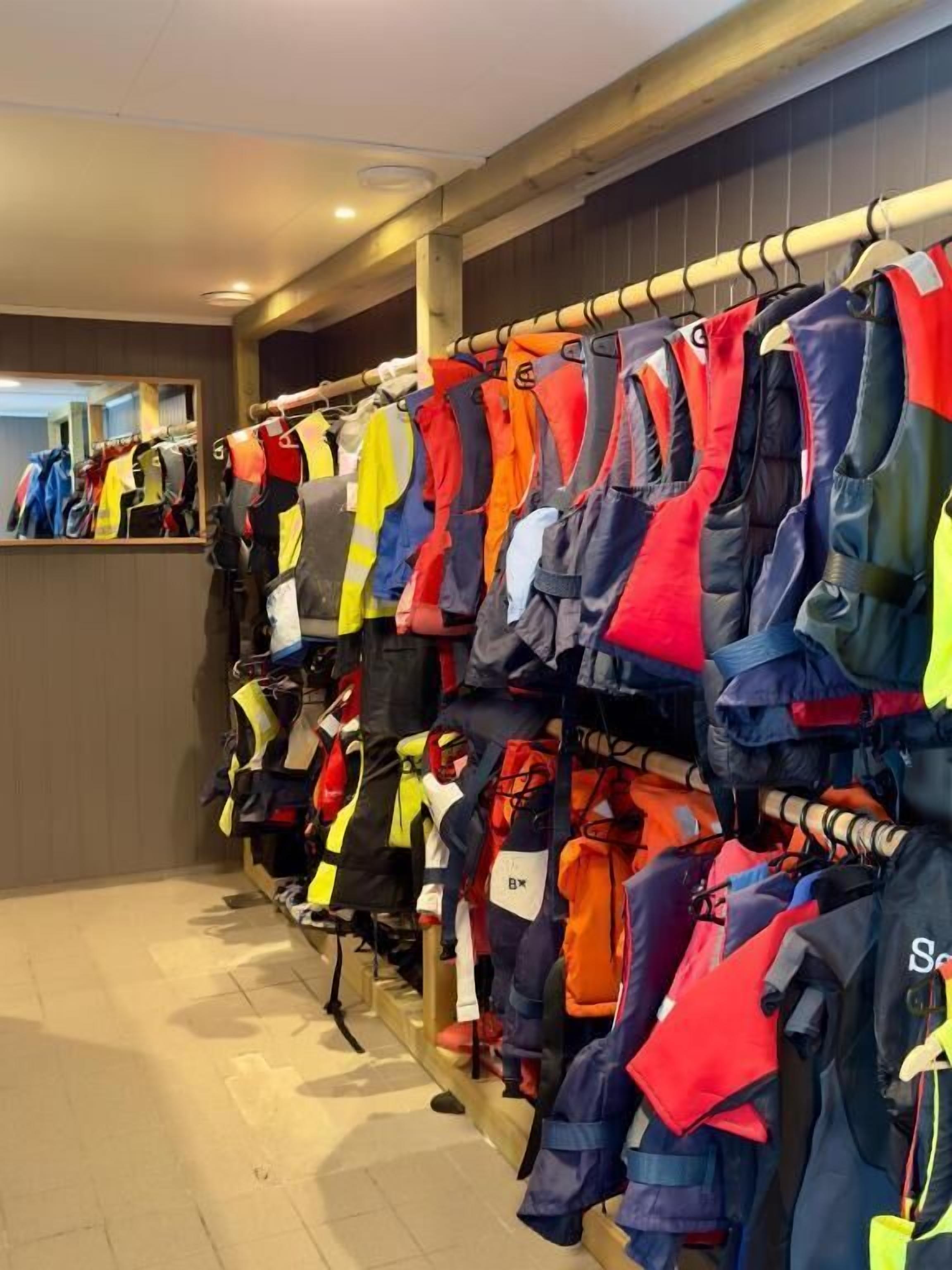 A clothing store with racks of jackets and vests.