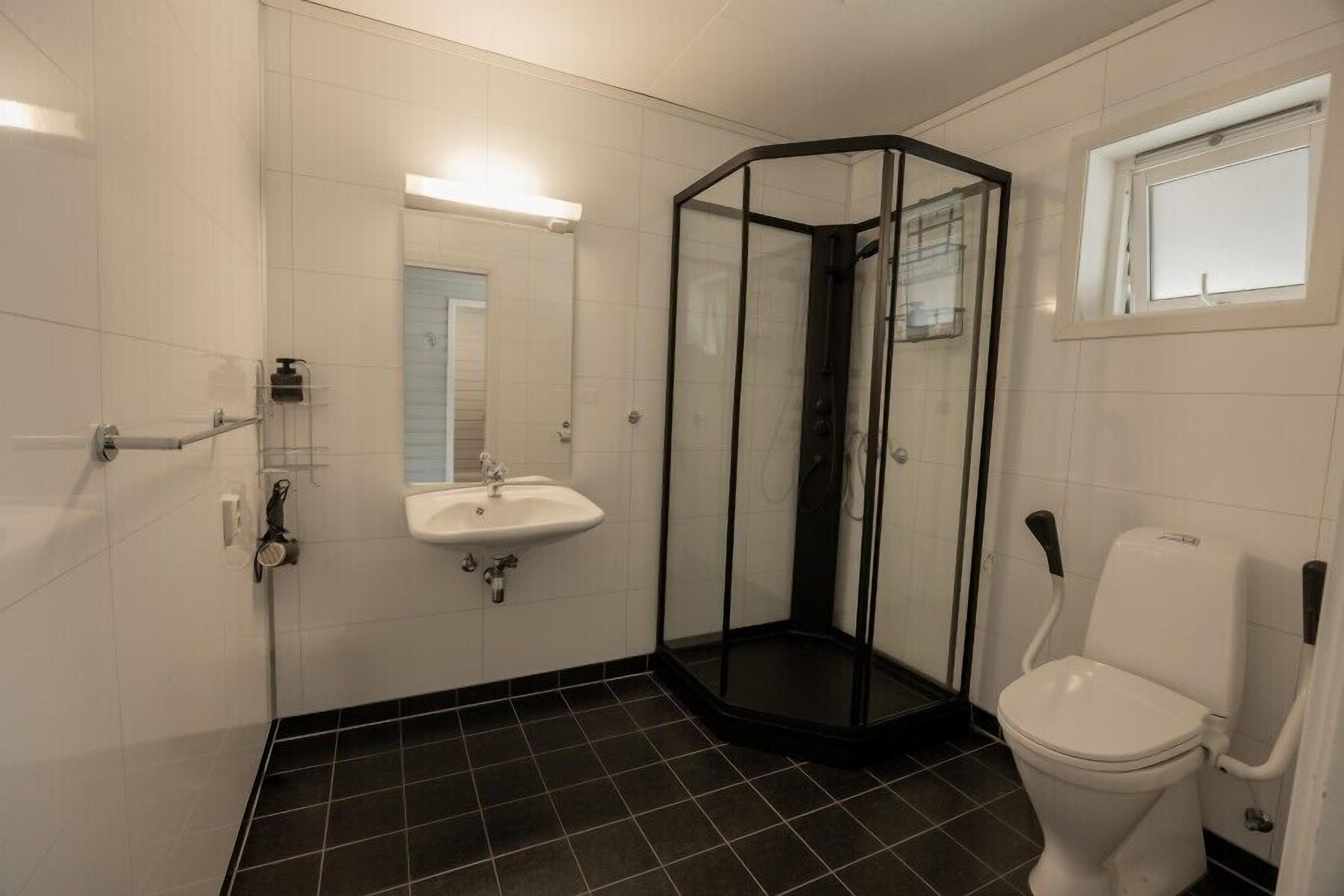 Une salle de bain avec une douche à parois de verre, un lavabo blanc et des toilettes.