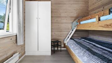 A compact bedroom with a bunk bed, a wardrobe, and a small table.