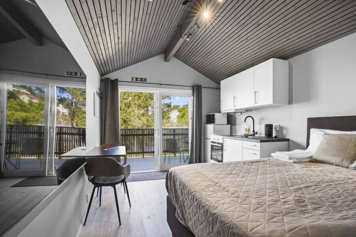 Un dormitorio moderno con una cama grande, un escritorio y una kitchenette.