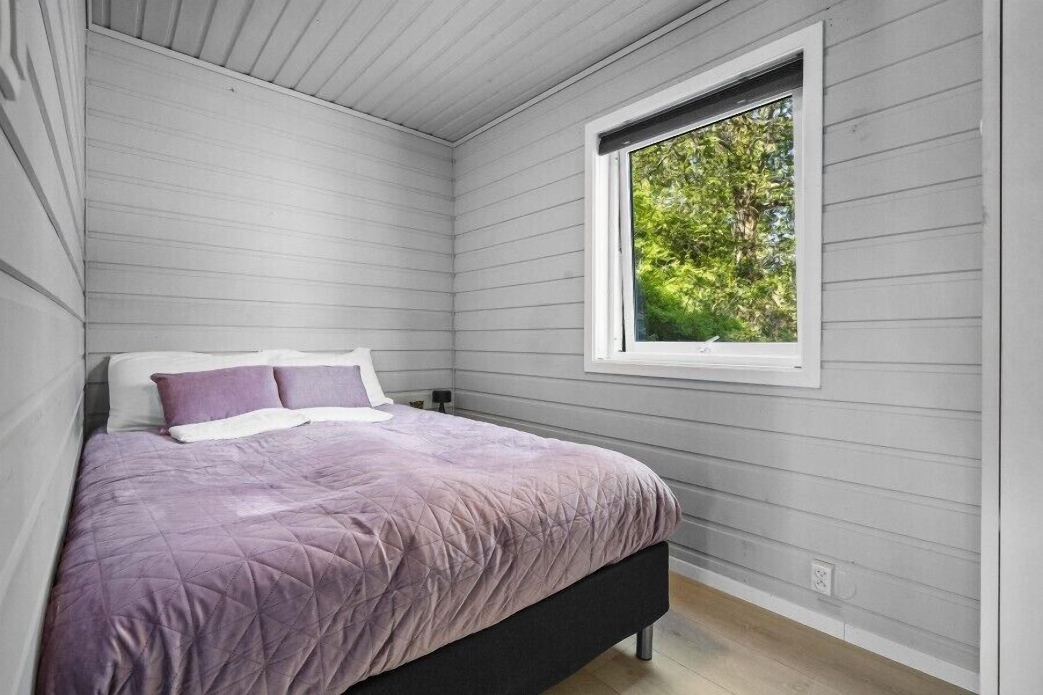 Une chambre à coucher avec un lit, une fenêtre et une vue sur les arbres.