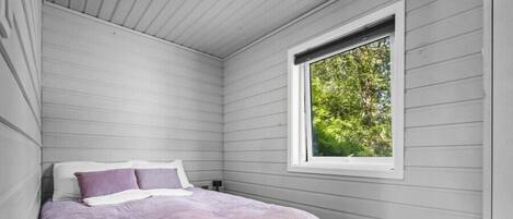 A bedroom with a bed, a window, and a view of trees.
