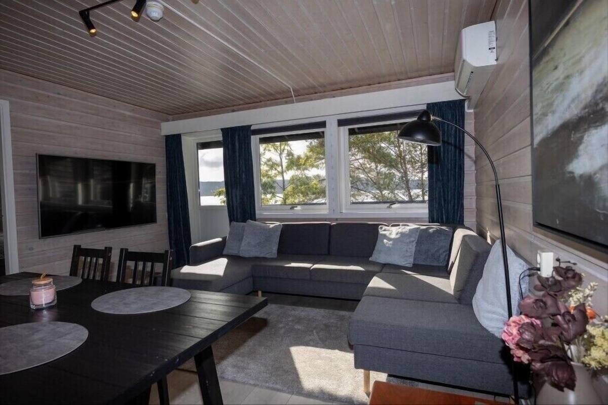 Una sala de estar moderna con un sofá modular, un televisor de pantalla plana y una zona de comedor con mesa y sillas.