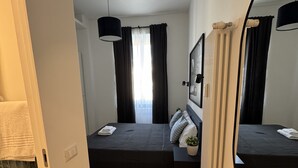Un dormitorio pequeño con cama, mesita de noche y un espejo grande.