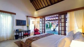 Habitación de hotel con una cama grande, un escritorio, una silla y vistas a una piscina a través de una puerta abierta.