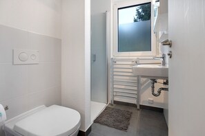 Une salle de bain moderne équipée de toilettes, d’une douche et d’un lavabo.