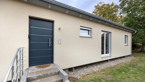 A modern building with a dark door, a small window, and a set of concrete steps leading to a door.