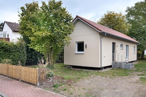 A small, single-story building with a red-tiled roof, a visible door, and a small window.