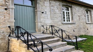 A stone building with a green door, white-framed windows, and a black metal staircase. - Historic Gardener’s House in Haltinne (Gesves)