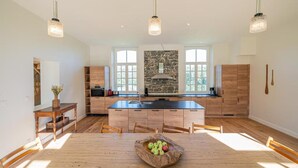 A modern kitchen with a central island, wooden cabinetry, and pendant lighting. - Historic Gardener’s House in Haltinne (Gesves)