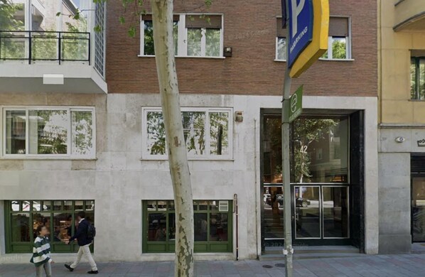 A multi-story building with a ground-floor entrance, a visible parking sign, and a tree in front. - Edmond Vibes Almagro Suites (Madrid)