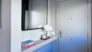 A bathroom with a mirror, a sink, a book titled "Living in Morocco," and a vase with white flowers. - Edmond Vibes Almagro Suites (Madrid)