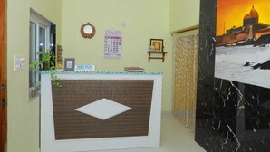 A reception desk with a calendar, a framed picture, and a small shelf with items. - Farmdean Holiday Home (Nagercoil)