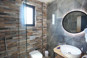 Une salle de bain moderne avec une douche à parois de verre, un meuble-lavabo en bois, un miroir rond et un mur en marbre.
