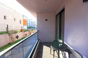 A balcony with a glass railing, a small table, and a chair. - Hotel Citrus (Ksamil)