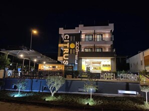 Ein modernes Hotel mit einem gut sichtbaren 'CITRUS'-Schild, Außenbestuhlung und einem gut beleuchteten Eingang.
