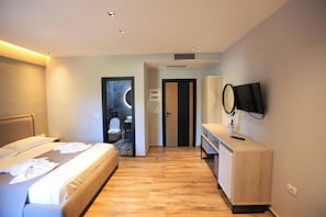 A modern hotel room with a bed, bedside table, TV, and a view of the bathroom. - Hotel Citrus (Ksamil)