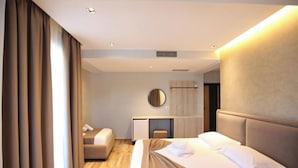 Ein modernes Hotelzimmer mit einem großen Bett, einem Schreibtisch und einer kleinen Sitzecke.