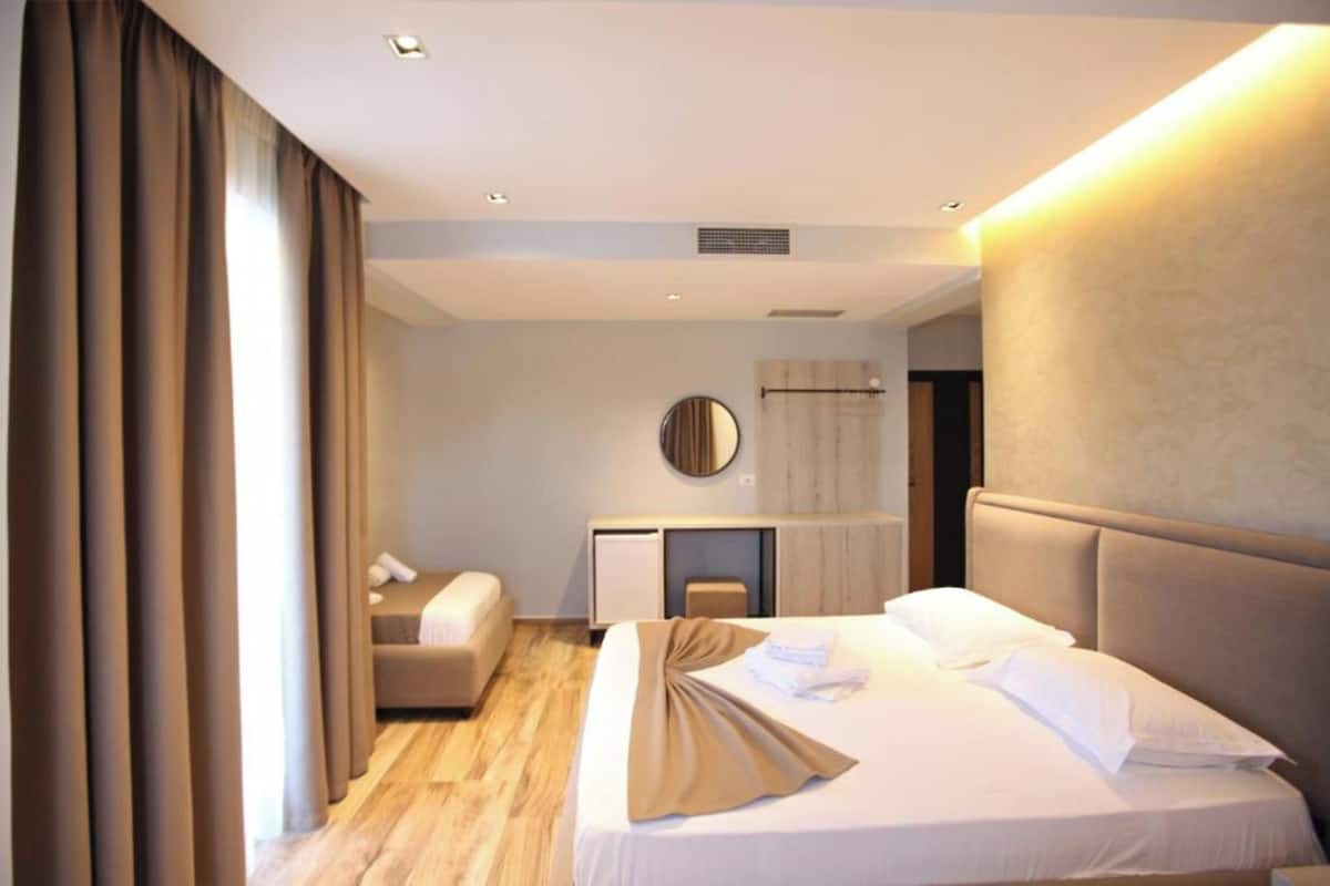 A modern hotel room with a large bed, a desk, and a small seating area.