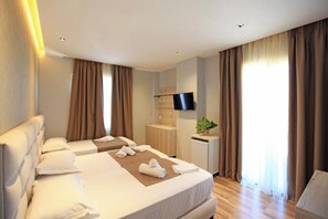 Une chambre d’hôtel avec deux lits, une télévision, un bureau et une fenêtre avec des rideaux.