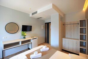 A modern hotel room with a bed, a desk, a TV, a shower area, and a wooden cabinet. - Hotel Citrus (Ksamil)