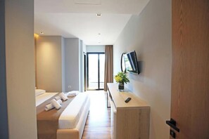 Une chambre d’hôtel moderne avec un grand lit, un bureau avec une télévision et une vue sur l’extérieur.
