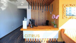 Eine Rezeption mit der Aufschrift "CITRUS", gestaltet als Holzlamelle, ein Computer und eine Vase mit Blumen.