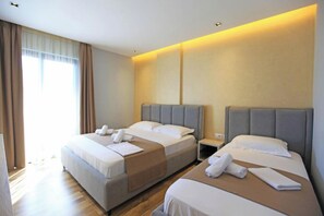 Une chambre d’hôtel avec deux lits, une table de chevet et une fenêtre avec des rideaux.