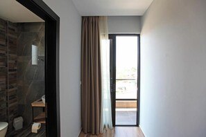 A modern bathroom with a stone wall, a toilet, and a shower area. - Hotel Citrus (Ksamil)