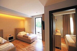 Une chambre d’hôtel avec un lit, un bureau et une chaise. Il y a une fenêtre avec des rideaux et une vue sur la verdure à l’extérieur.